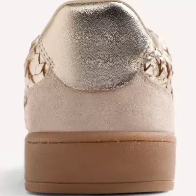 Parte traseira de ténis bege com pala dourada metálica