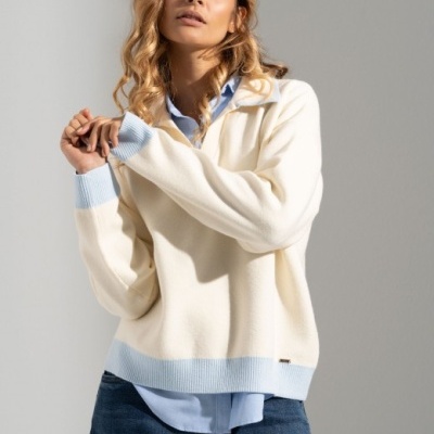 Mulher veste suéter creme com detalhes azul claro e calças de ganga azul escuro