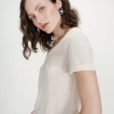 Mulher de cabelo ondulado com camiseta branca e brincos prateados