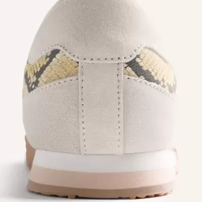 Ténis creme com padrão de pele de cobra na parte traseira.