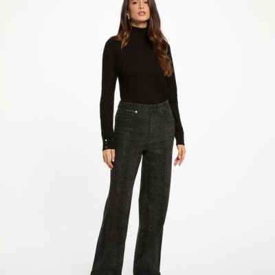 Mulher vestindo camisola preta de gola alta e calças pretas largas com padrão texturizado