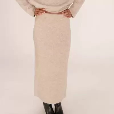 Saia midi justa bege de malha com botas pretas.