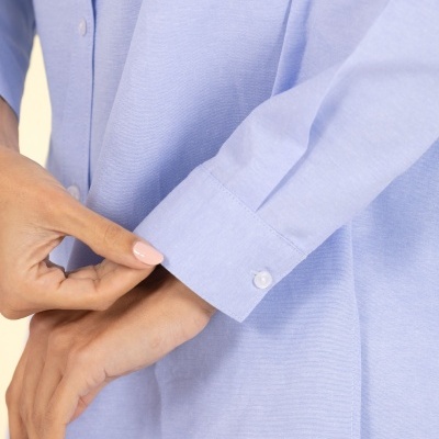 Camisa azul clara com botões brancos e logo metálico FRCE