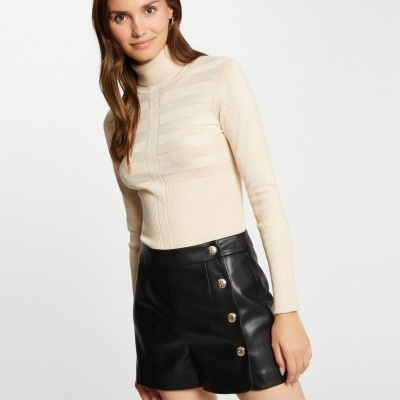 Mulher com top creme e saia preta de couro em fundo branco