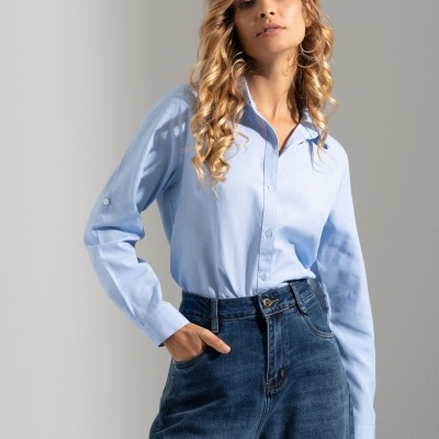 Mulher com camisa azul clara de manga comprida e calças de ganga azul escuro