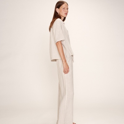 Conjunto listrado de camisa e calças femininas com sandálias pretas em fundo branco