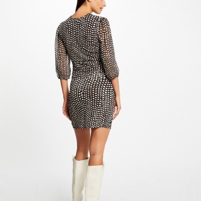 Vestido curto preto com padrão de círculos brancos e botas brancas.