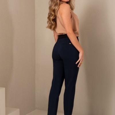 Mulher de costas com calças azuis, top cor de pele e sapatos nude