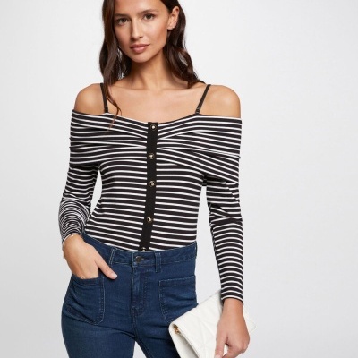 Mulher a usar top às riscas preto e branco com botões e calças jeans azuis.