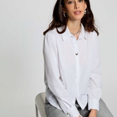 Mulher com camisa branca de algodão e jeans cinzentos sentada