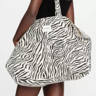 Mala grande estampada tipo zebra preto e branco com etiqueta Grace & Mila, usada ao ombro.