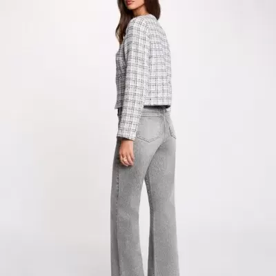 Modelo veste calças de ganga cinza largas e casaco xadrez curto com sapatos pretos.