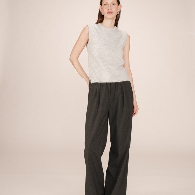 Mulher com colete cinza claro e calças pretas largas