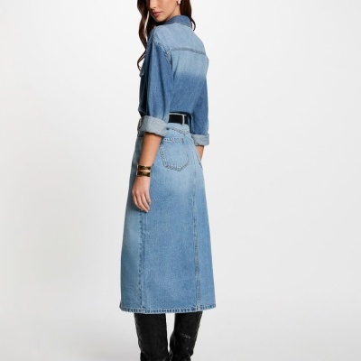 Mulher de costas com camisa e saia de ganga, botas pretas, fundo branco