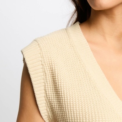 Colete de malha bege com padrão texturizado e decote em V