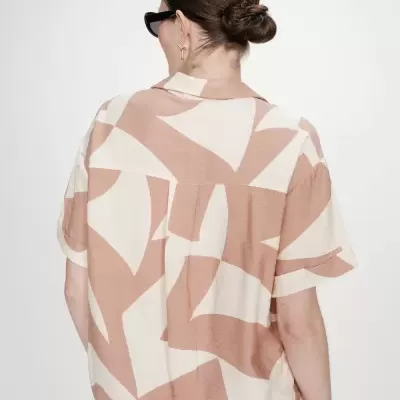 Camisa de manga curta com padrão abstrato bege e creme vista de costas.