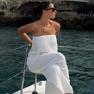 Mulher com vestido branco tomara que caia a bordo de um barco no mar