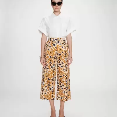 mulher com calças largas estampadas, camisa branca e sapatos pretos