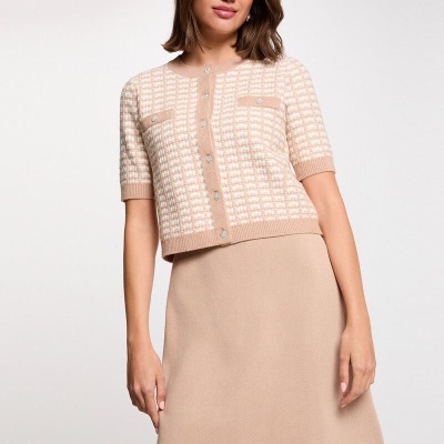 Mulher com top de malha bege e branca e saia bege