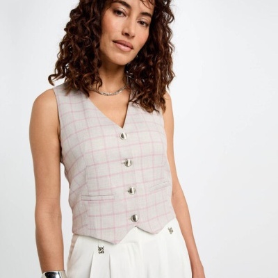 Colete xadrez rosa e branco com botões prateados, calças brancas e pulseira metálica