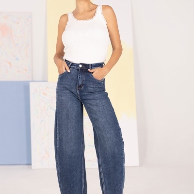 Mulher de camisola branca e calças de ganga azuis em estúdio com quadros abstractos.