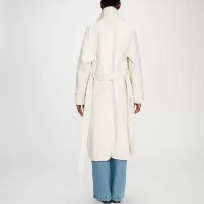 Casaco creme comprido com cinto e calças de ganga largas vista de costas