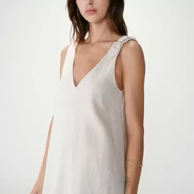 Vestido bege claro com decote em V e nó na alça, vestido por mulher com bracelete dourado