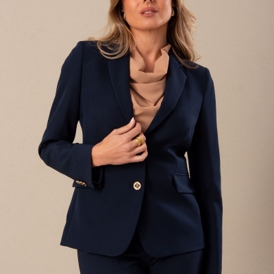 Mulher com blazer azul marinho e blusa bege clara em fundo bege