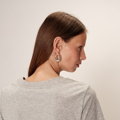Pessoa de costas com t-shirt cinza e brincos de argola prateados