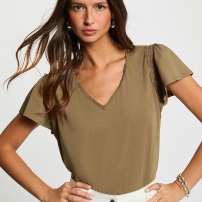 T-shirt verde-oliva de manga curta com detalhes em renda usada por mulher com calças brancas