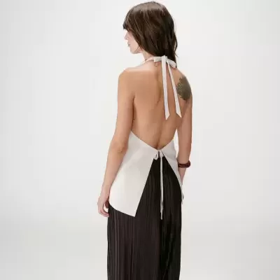 Mulher de costas com top branco sem costas e calças pretas plissadas