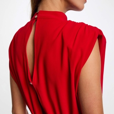 Vestido vermelho com costas abertas e botões prateados, usado por mulher