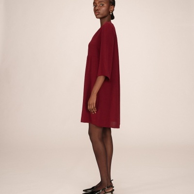 Vestido curto vinho com manga 3/4, collants pretos e sapatos pretos de tacão fino