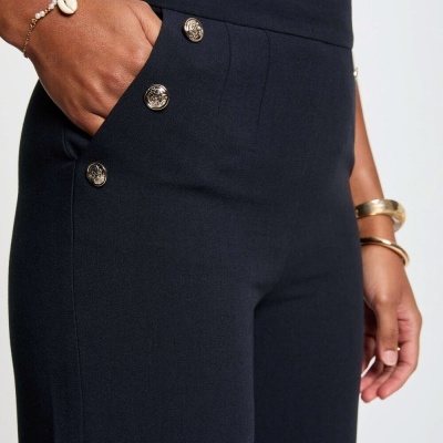 Calças azul escuro com botões metálicos e acessórios no pulso