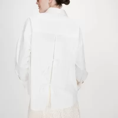 Camisa branca com laços nas costas e saia de renda bege