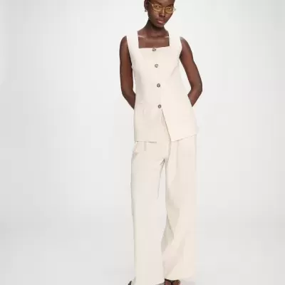 Mulher a usar colete creme com botões e calças largas creme em fundo branco