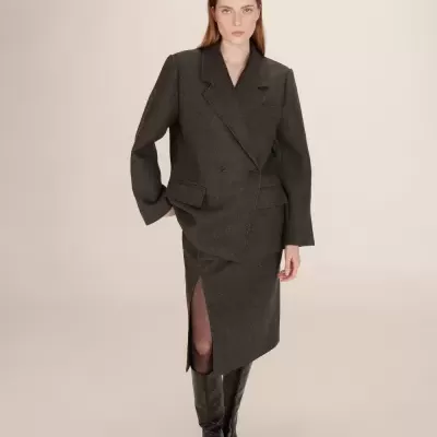 Conjunto de fato feminino cinza escuro com blazer e saia lápis, botas pretas.