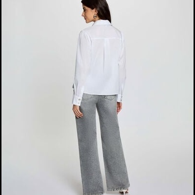 Mulher de costas com camisa branca e calças cinzentas largas