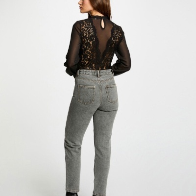 Mulher de costas com blusa preta de renda e calças de ganga cinza