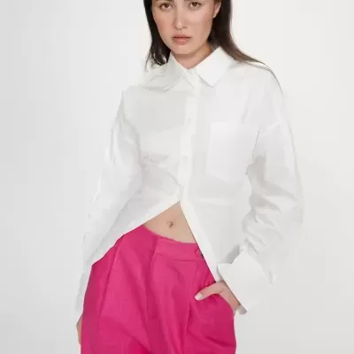 Camisa branca de mulher com calças rosa vibrante em fundo branco