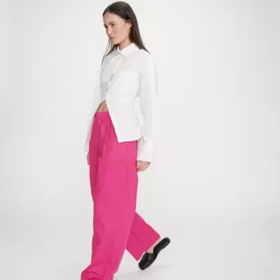 Mulher com camisa branca, calças largas rosa e chinelos pretos