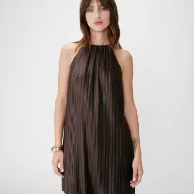 Top feminino plissado castanho escuro com calças a condizer num fundo branco liso