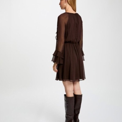 Mulher de costas vestindo vestido castanho escuro com mangas longas e botas pretas altas.