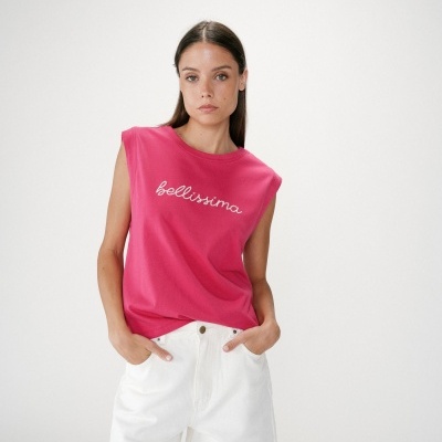 Mulher com camisola rosa sem mangas e calças brancas em fundo branco