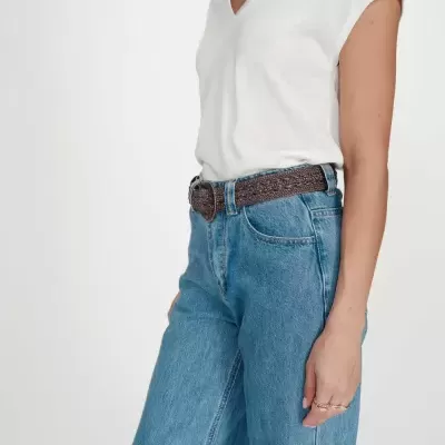 Pessoa com t-shirt branca, jeans azul e cinto castanho trançado