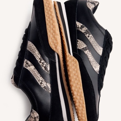 Sapatilhas pretas com padrão de pele de cobra e sola beige texturada.