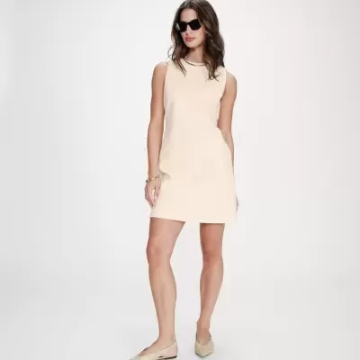 Vestido curto creme sem mangas com sapatos creme e óculos de sol pretos