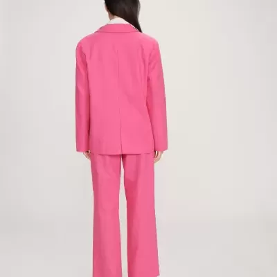 Mulher de costas a usar conjunto de fato rosa com blazer e calças largas