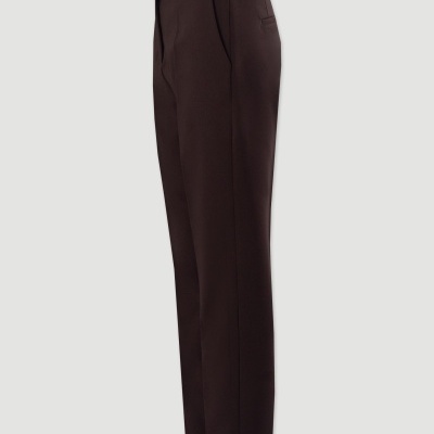 Calças castanhas de tecido liso com cós preto em fundo cinza.