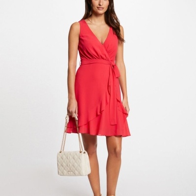 Vestido vermelho de senhora com mala bege e sandálias rasas douradas